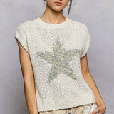 Woman wearing a textured white top with a star design on a plain background