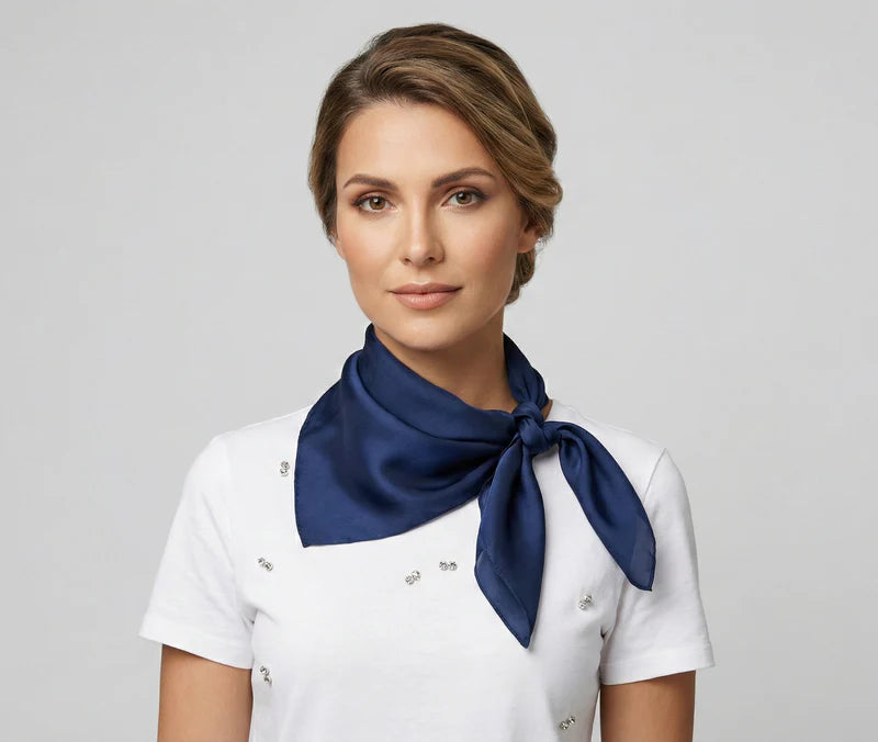 Woman wearing a white uniform with a navy blue scarf on a gray background