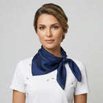 Woman wearing a white uniform with a navy blue scarf on a gray background