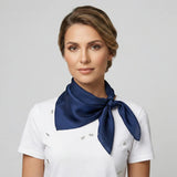 Woman wearing a white uniform with a navy blue scarf on a gray background