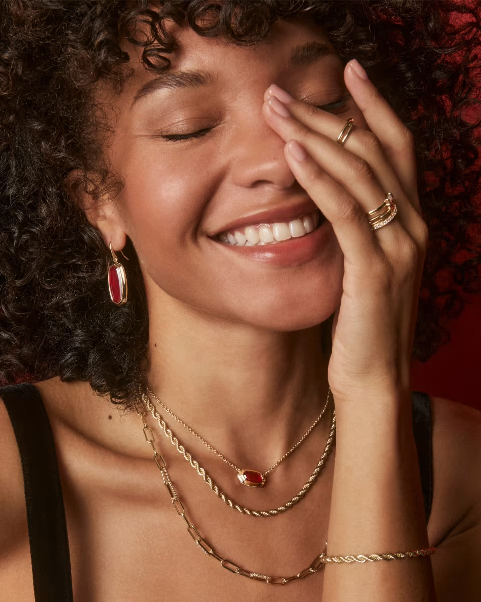 Woman wearing gold jewelry with a warm, soft focus background