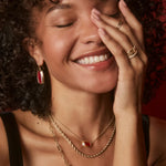 Woman wearing gold jewelry with a warm, soft focus background