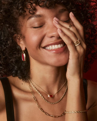 Woman wearing gold jewelry with a warm, soft focus background