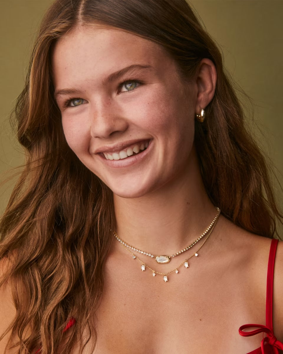 Woman wearing a red top and layered necklaces against a green background