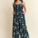 Woman wearing a blue floral jumpsuit on a beige background