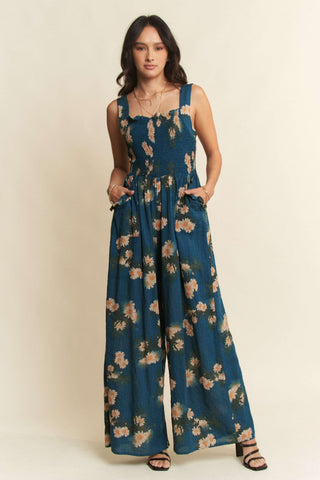 Woman wearing a blue floral jumpsuit on a beige background
