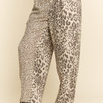 Leopard print pants worn by a person on a beige background