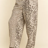 Leopard print pants worn by a person on a beige background