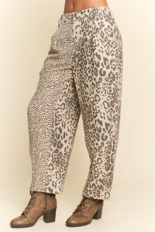 Leopard print pants worn by a person on a beige background