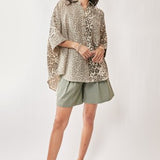 Woman wearing a leopard print top and green shorts on a white background