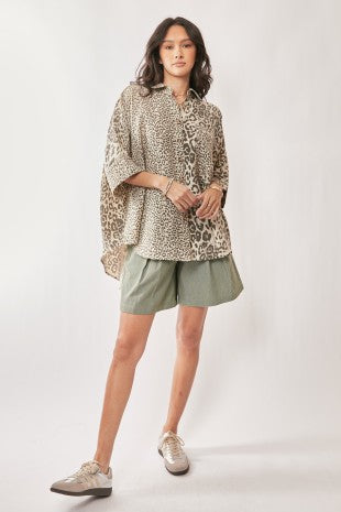 Woman wearing a leopard print top and green shorts on a white background