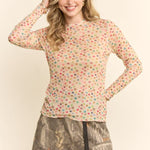 Woman wearing a colorful polka dot top and patterned skirt on a plain background