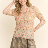 Woman wearing a colorful polka dot top and patterned skirt on a plain background