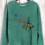 Green sweatshirt with Texas graphic on a wooden hanger against a wooden background