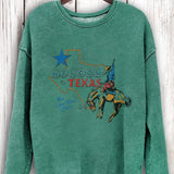 Green sweatshirt with Texas graphic on a wooden hanger against a wooden background