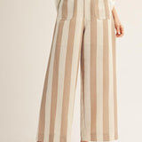 Person wearing beige and white striped pants on a plain background