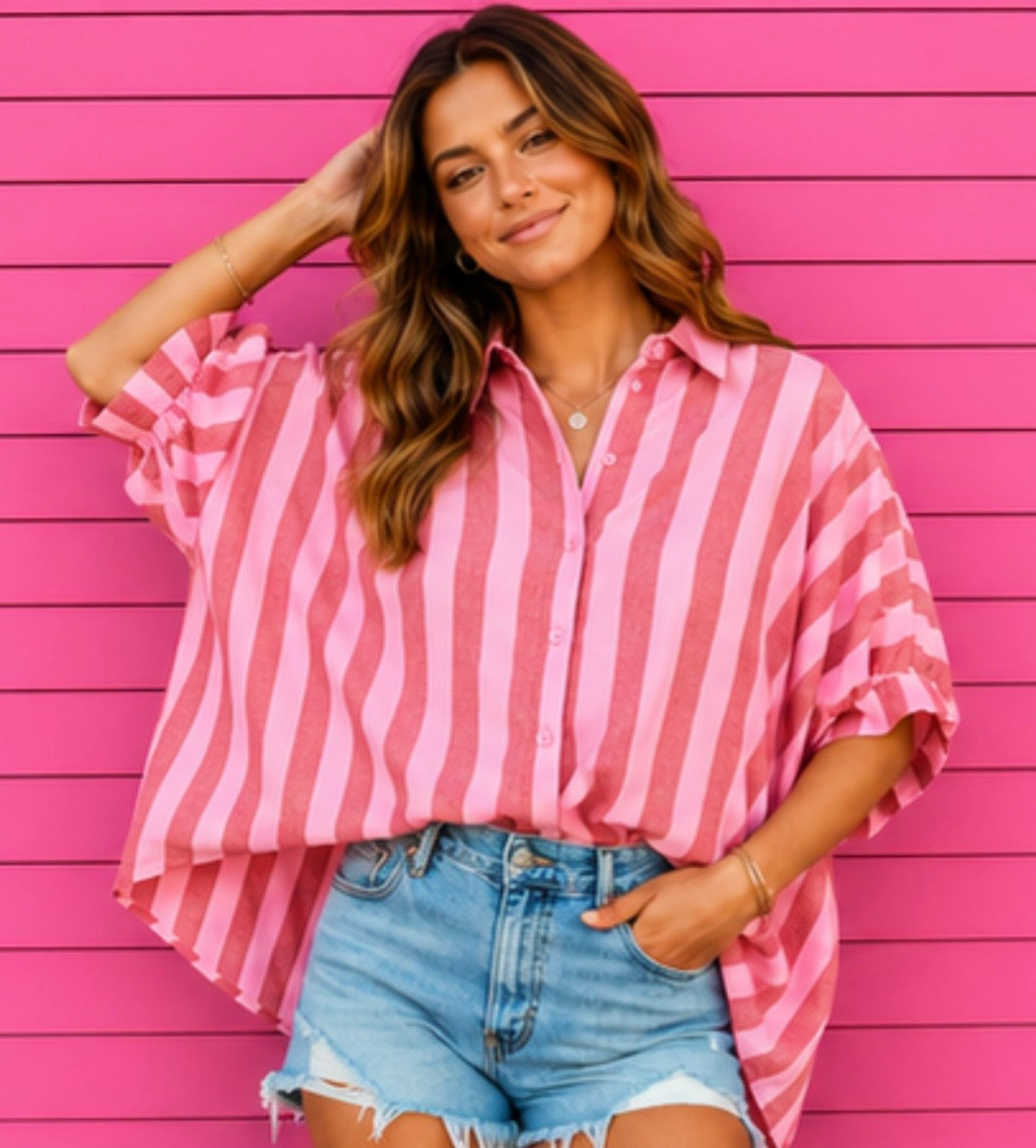 Woman wearing a pink and white striped shirt over a blue denim shirt against a pink wooden background