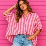 Woman wearing a pink and white striped shirt over a blue denim shirt against a pink wooden background