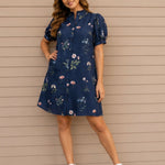 Woman wearing a navy floral dress against a beige wall