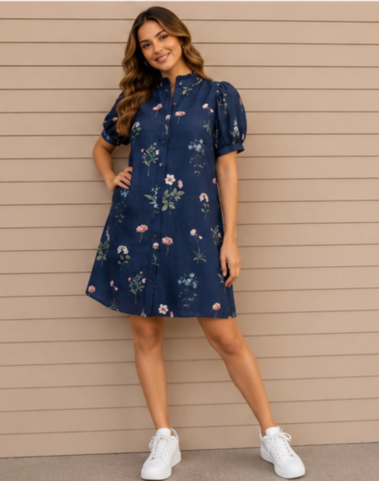 Woman wearing a navy floral dress against a beige wall