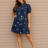 Woman wearing a navy floral dress against a beige wall