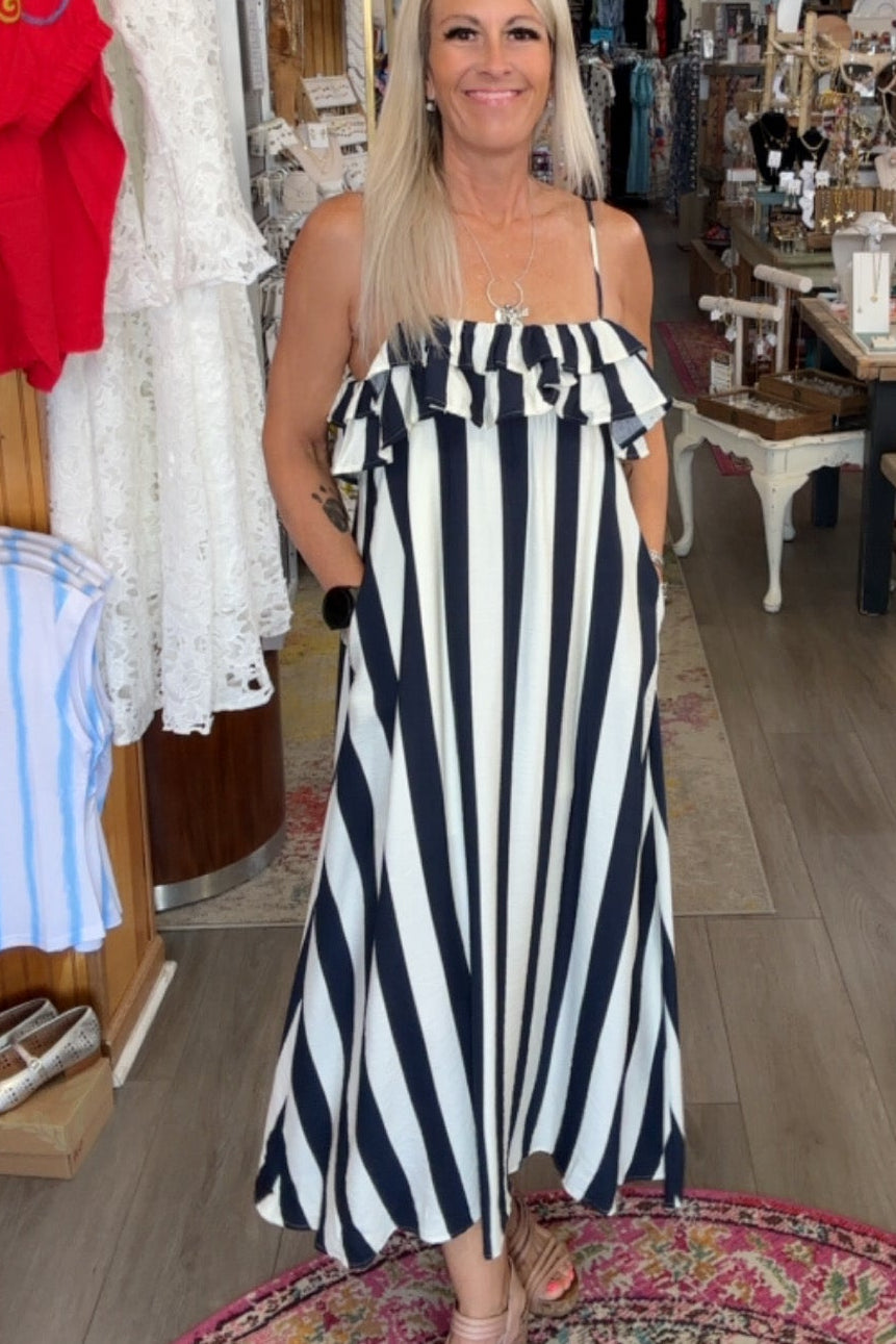 Woman in a black and white striped dress standing in a store with various items on display.