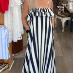 Woman in a black and white striped dress standing in a store with various items on display.