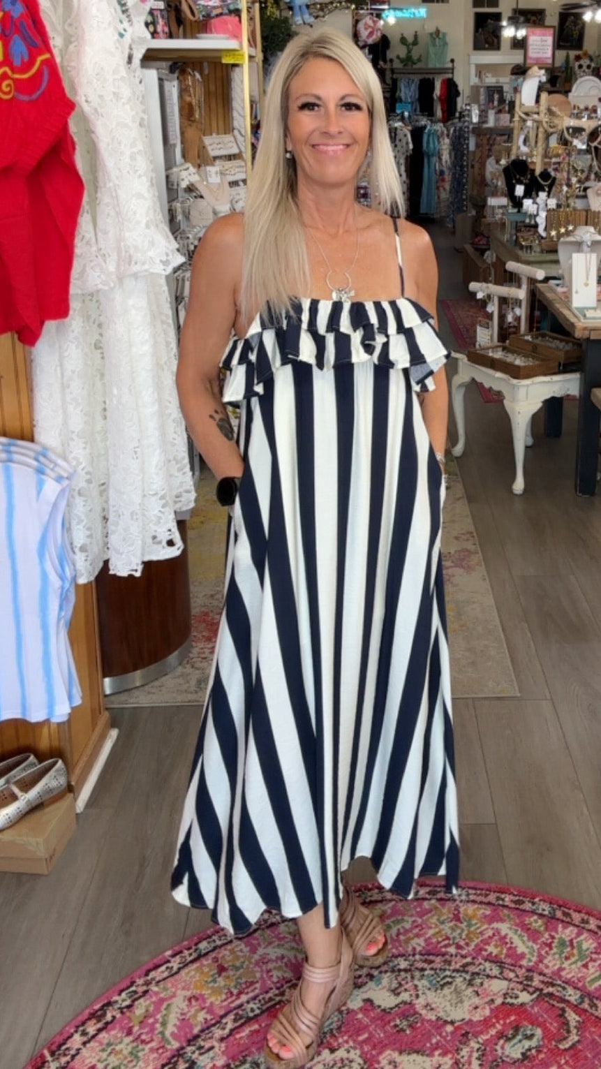 Woman in a black and white striped dress standing in a store with various items on display.