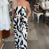 Woman in a black and white patterned jumpsuit standing in a store with various items on display.