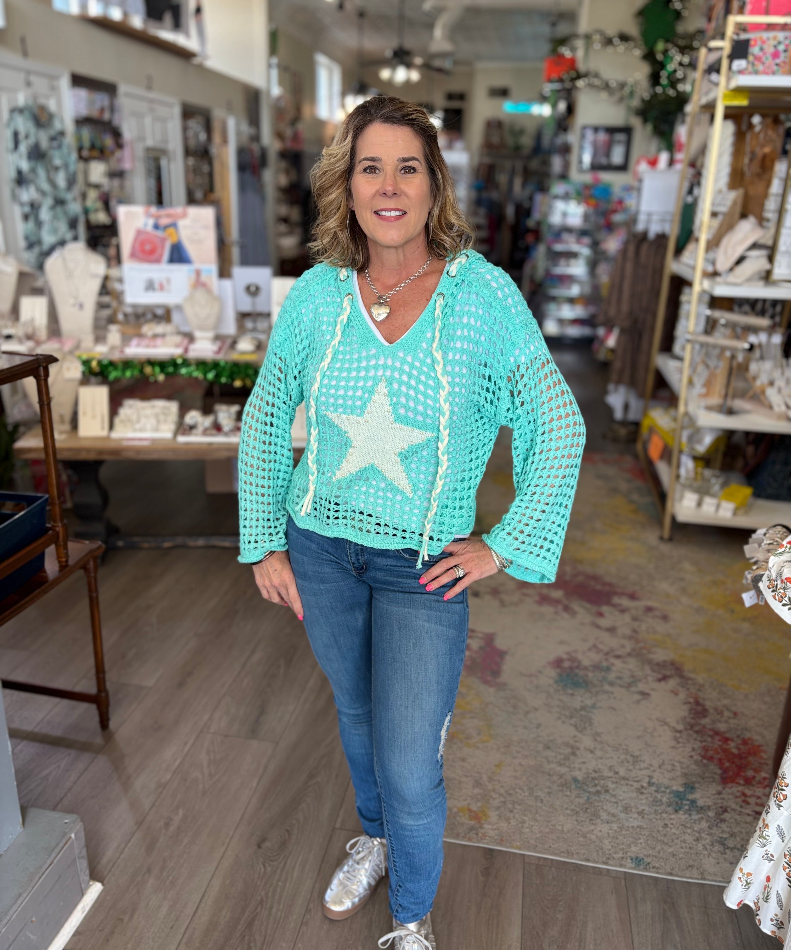 Woman wearing a light blue crochet top with a star design in a store setting.