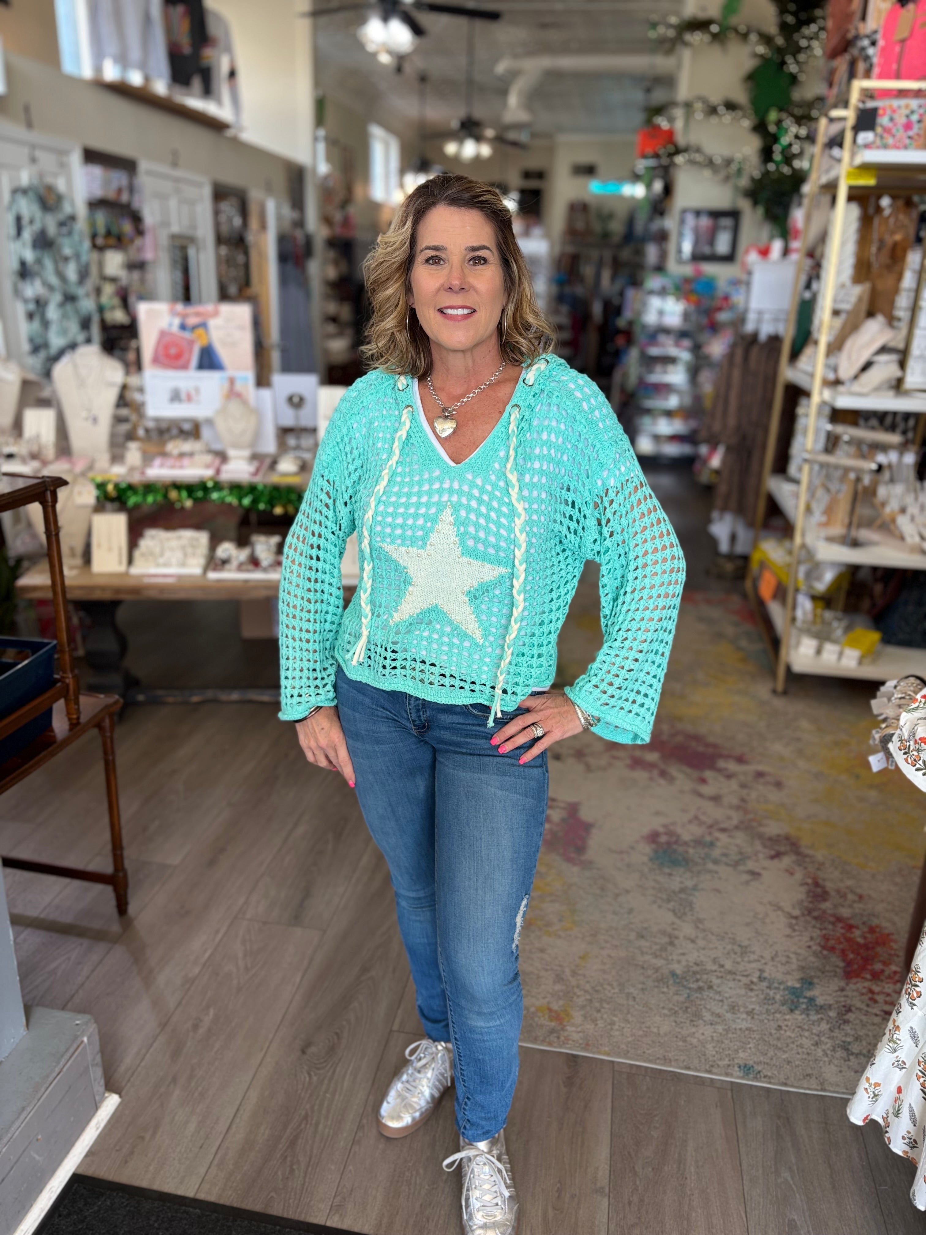 Woman wearing a light blue crochet top with a star design in a store setting.