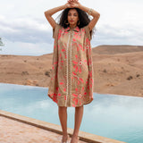Woman in a floral dress standing by a pool with mountains in the background