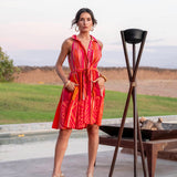 Woman in an orange dress standing outdoors near a pool with a scenic background