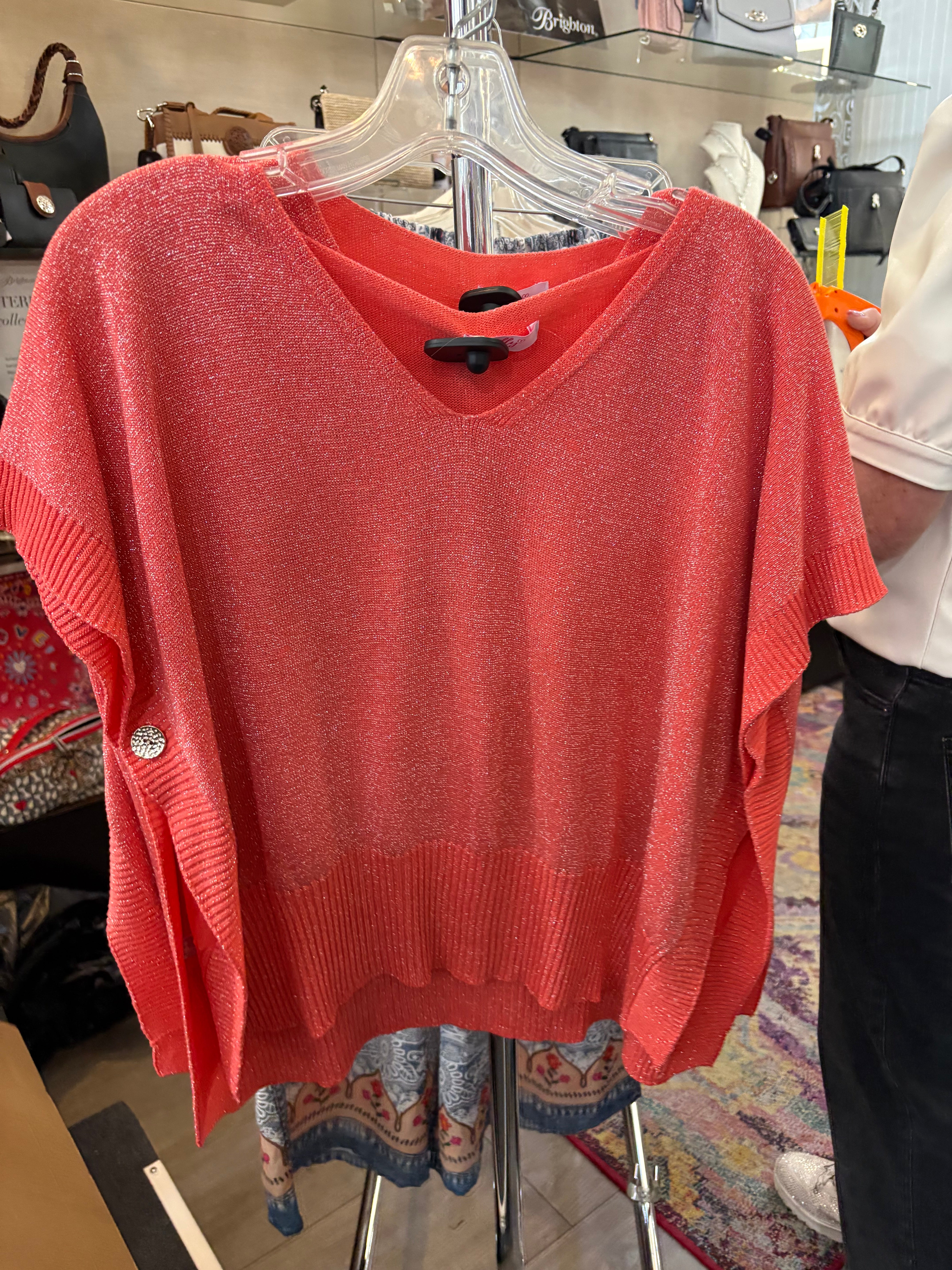 Red sweater on a hanger with a blurred store interior background