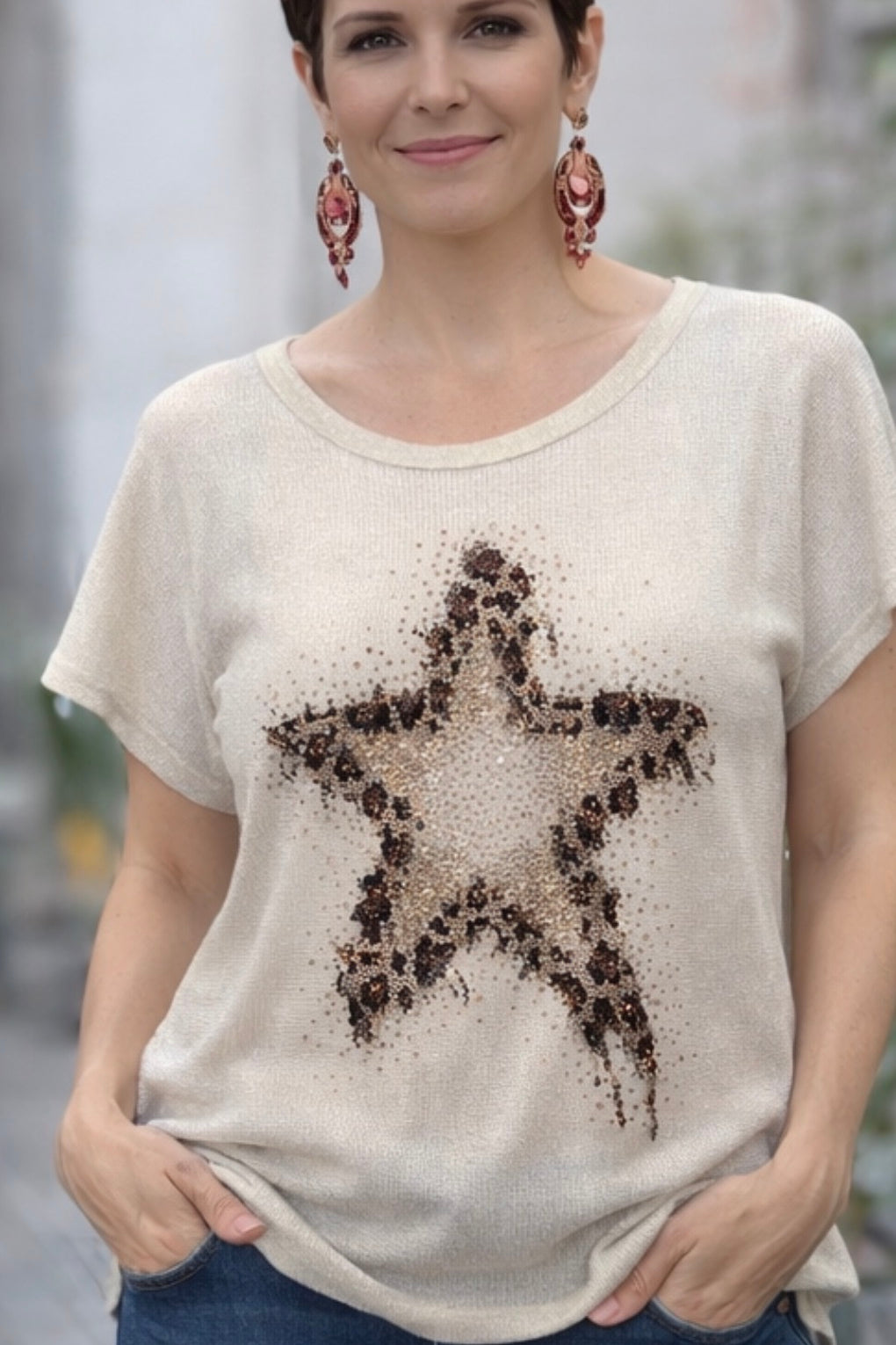 Woman wearing a beige t-shirt with a star design, standing outdoors.