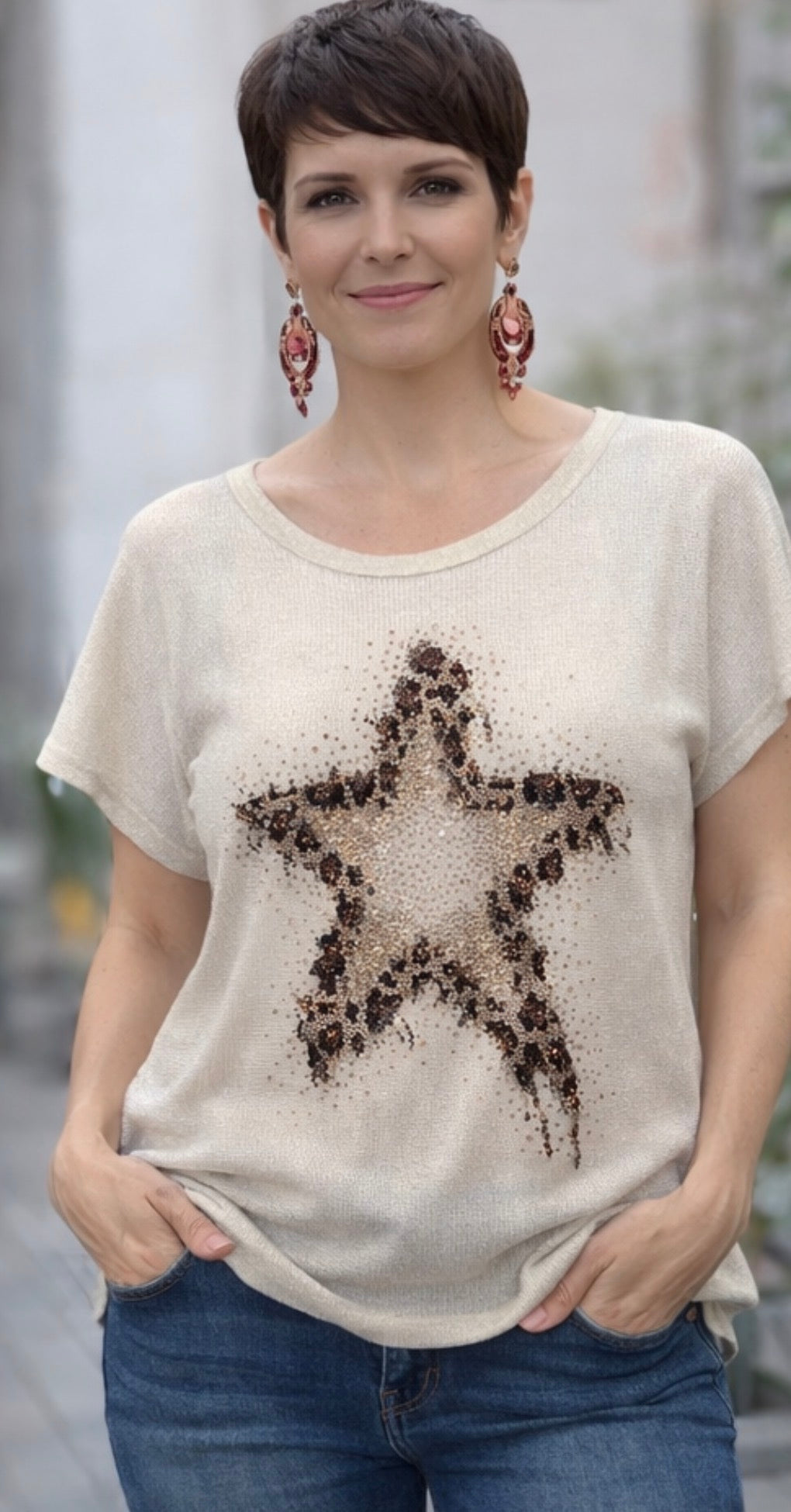 Woman wearing a beige t-shirt with a star design, standing outdoors.
