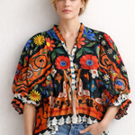 Woman wearing a colorful patterned blouse with floral designs against a white background