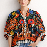Woman wearing a colorful patterned blouse with floral designs against a white background