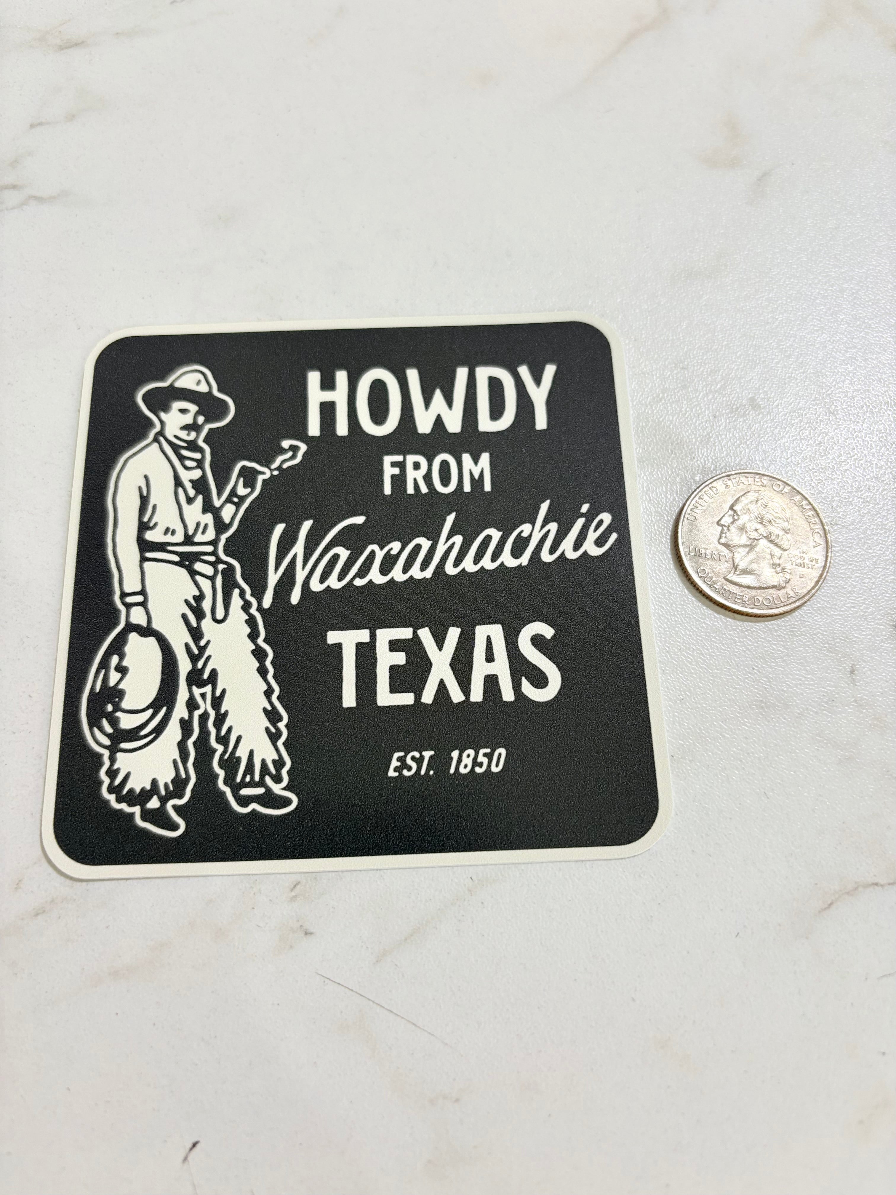 Sticker with 'Howdy from Waxahachie Texas' text and a cowboy graphic on a marble surface.