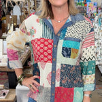 Woman wearing a colorful patchwork shirt in a store setting