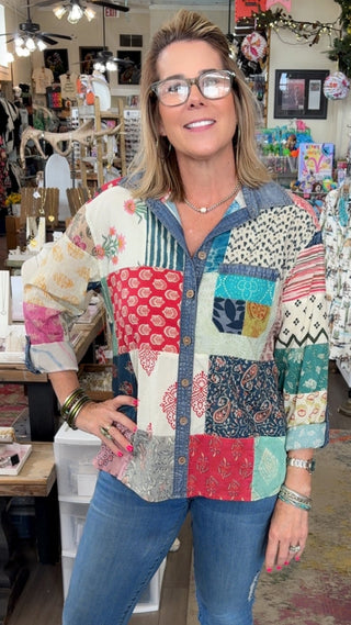 Woman wearing a colorful patchwork shirt in a store setting