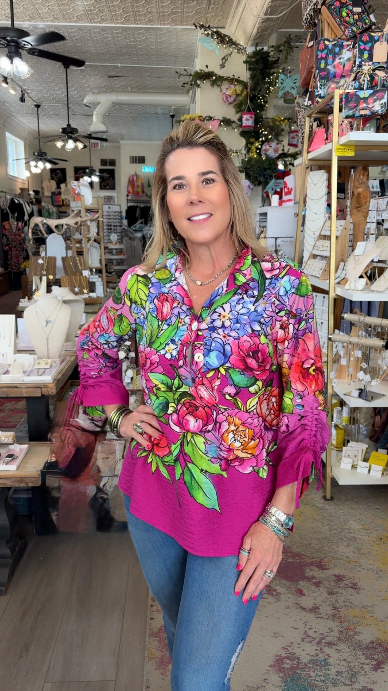 Woman wearing a colorful floral blouse in a store setting