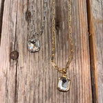 Two necklaces with rectangular gemstones on a wooden surface