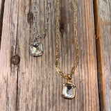 Two necklaces with rectangular gemstones on a wooden surface