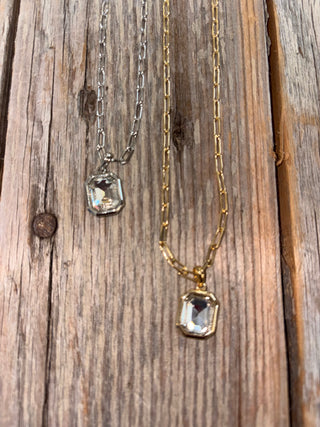 Two necklaces with rectangular gemstones on a wooden surface
