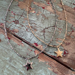 Two star-shaped necklaces on a textured wooden surface