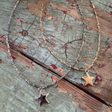 Two star-shaped necklaces on a textured wooden surface
