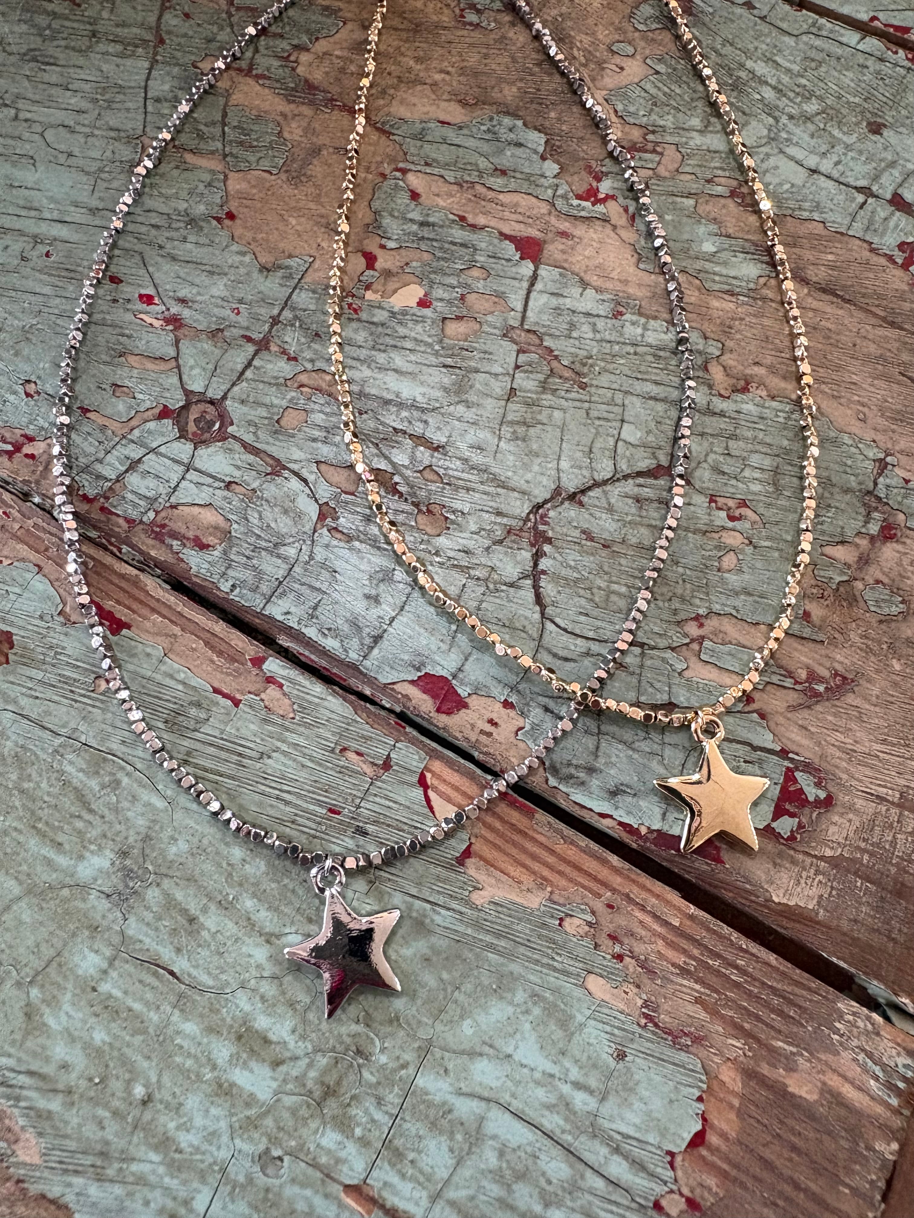 Two star-shaped necklaces on a textured wooden surface
