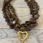 Necklace with brown heart-shaped beads and a gold heart clasp on a wooden surface
