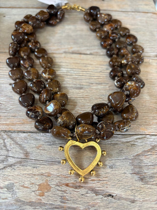 Necklace with brown heart-shaped beads and a gold heart clasp on a wooden surface